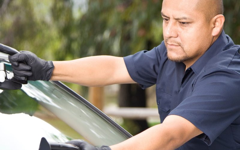 Technicien posant un pare-brise aux ventouses sur le lieu d'intervention